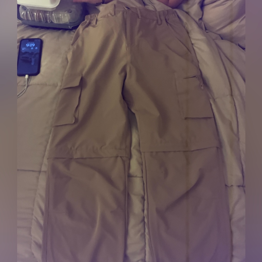 Pale nylon parachute cargo trousers laid flat with thigh pockets and a drawcord hem